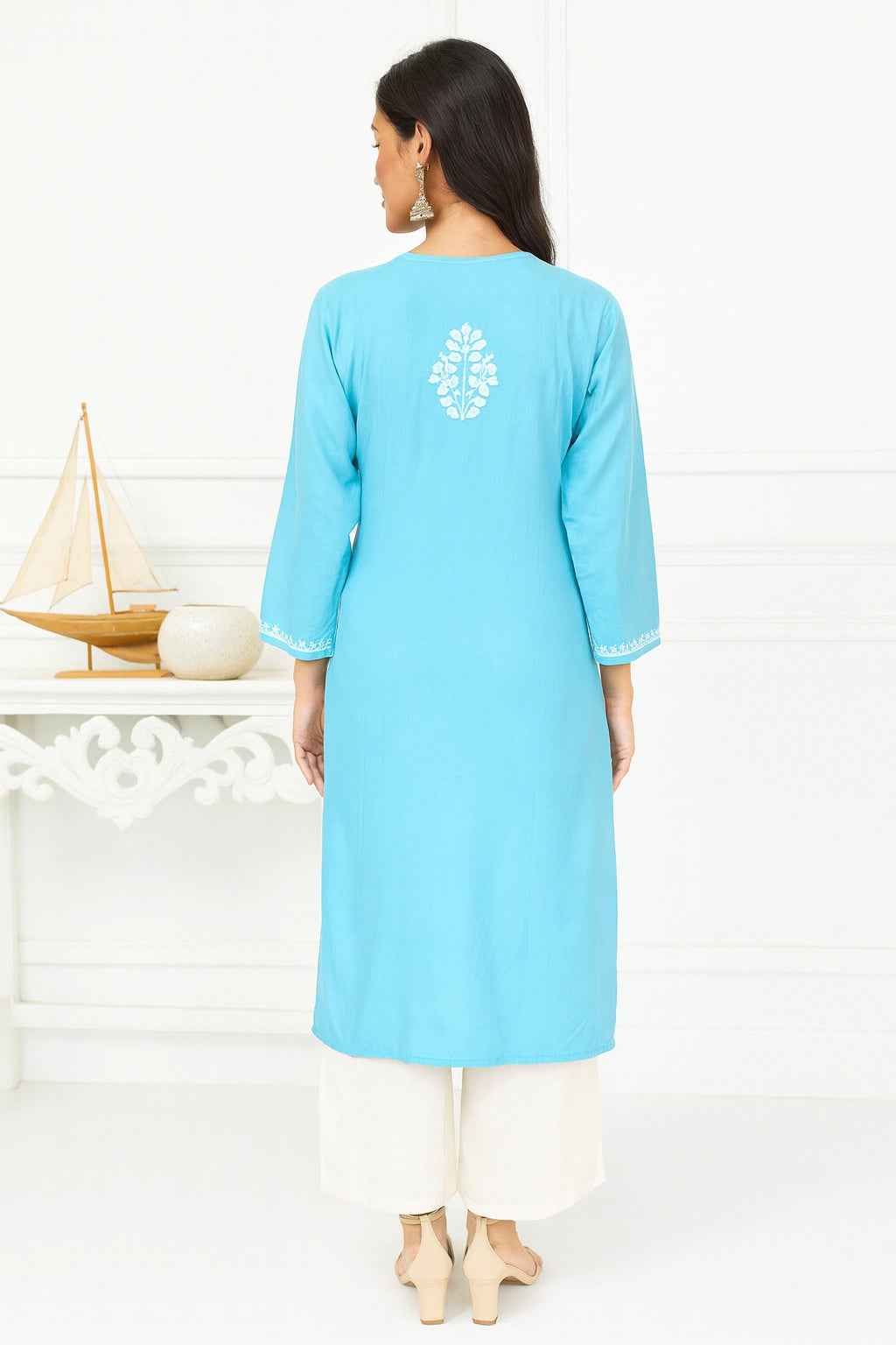 Woman wearing a light blue kurta with white embroidery on a white background
