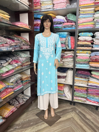 Mannequin wearing a light blue embroidered kurta with white pants in a fabric store.