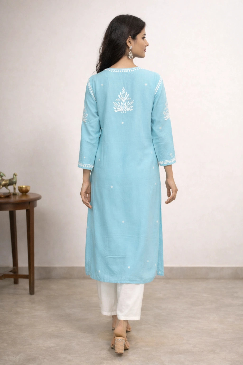 Woman wearing a light blue kurta with white embroidery on a plain background