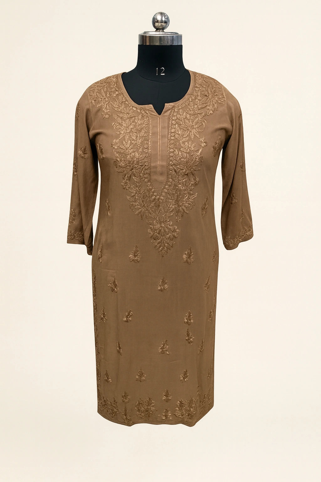 Brown embroidered dress on a mannequin against a beige background
