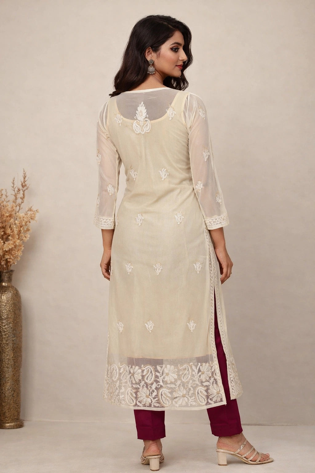 Woman wearing a cream embroidered kurta with maroon pants against a neutral background