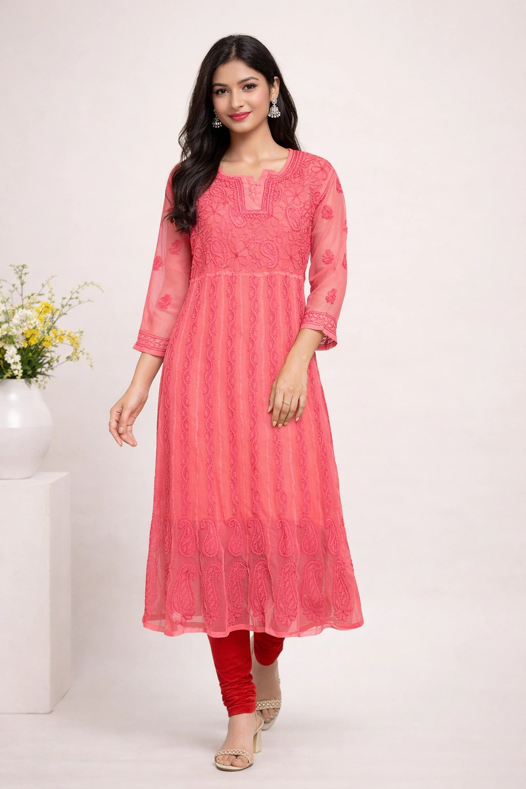 Woman wearing a lucknowi chikankari pink kurta with red pants on a white background