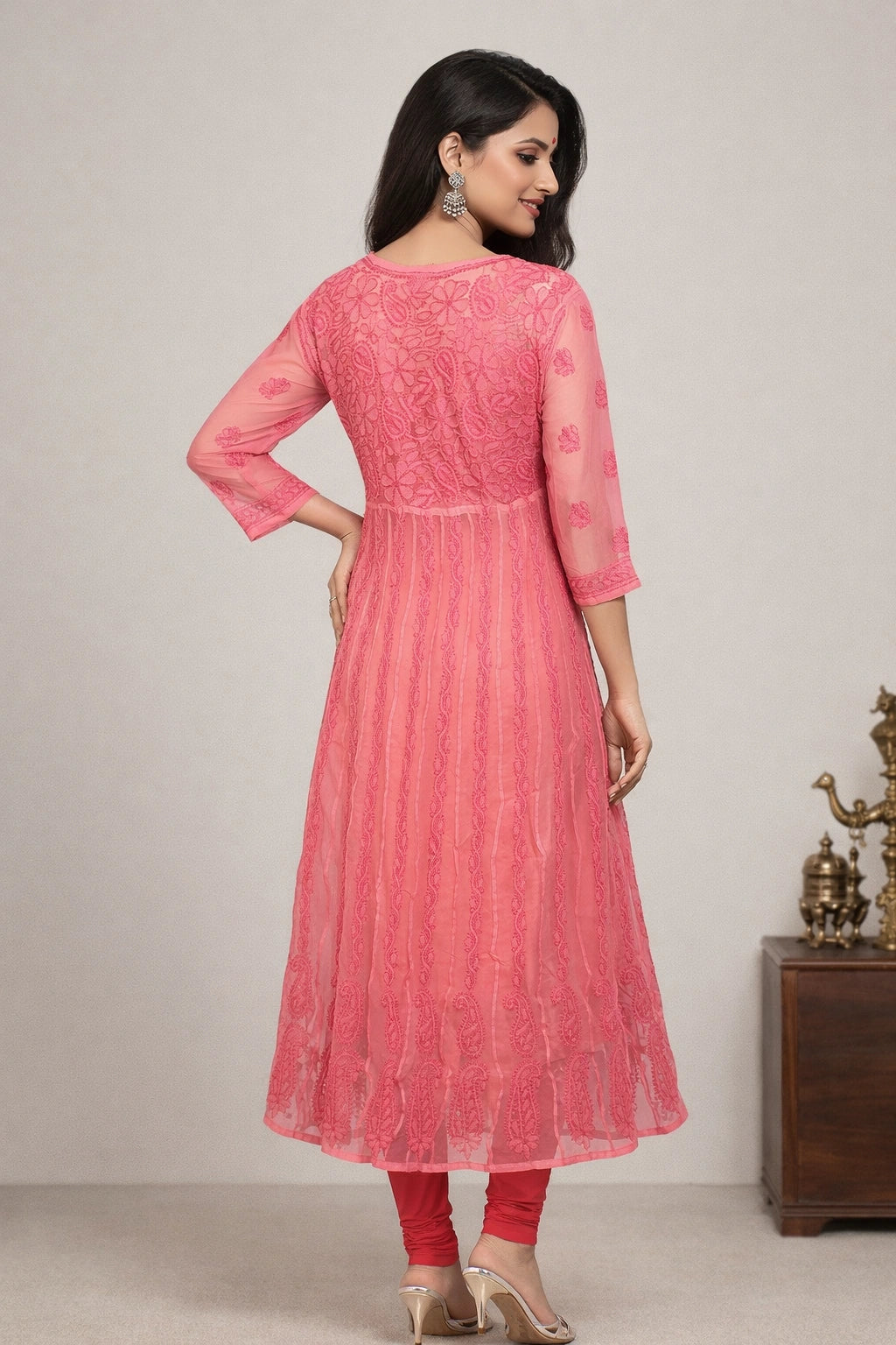 Woman wearing a pink embroidered kurta with red pants against a neutral background