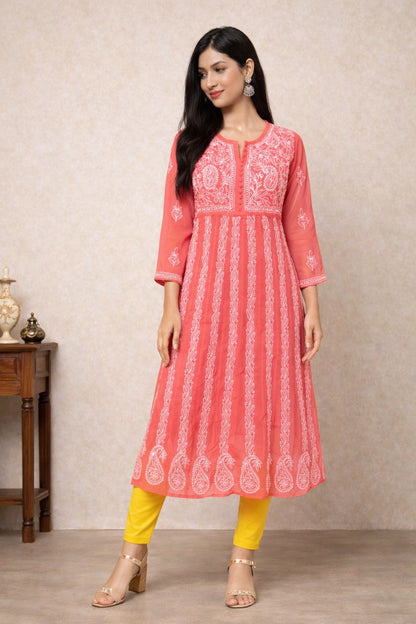 Woman wearing a pink embroidered kurta with yellow pants against a beige wall.
