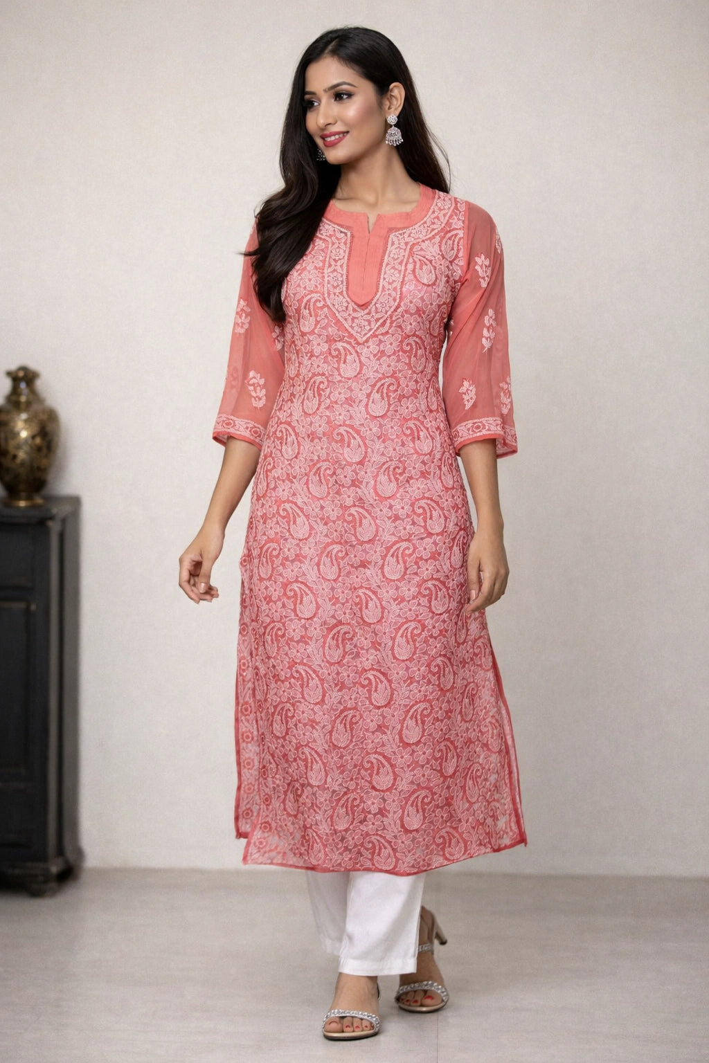 Woman wearing a lucknowi chikankari pink kurta with white patterns on a plain background