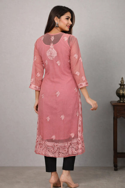 Woman wearing a pink embroidered kurta with black pants against a gray background