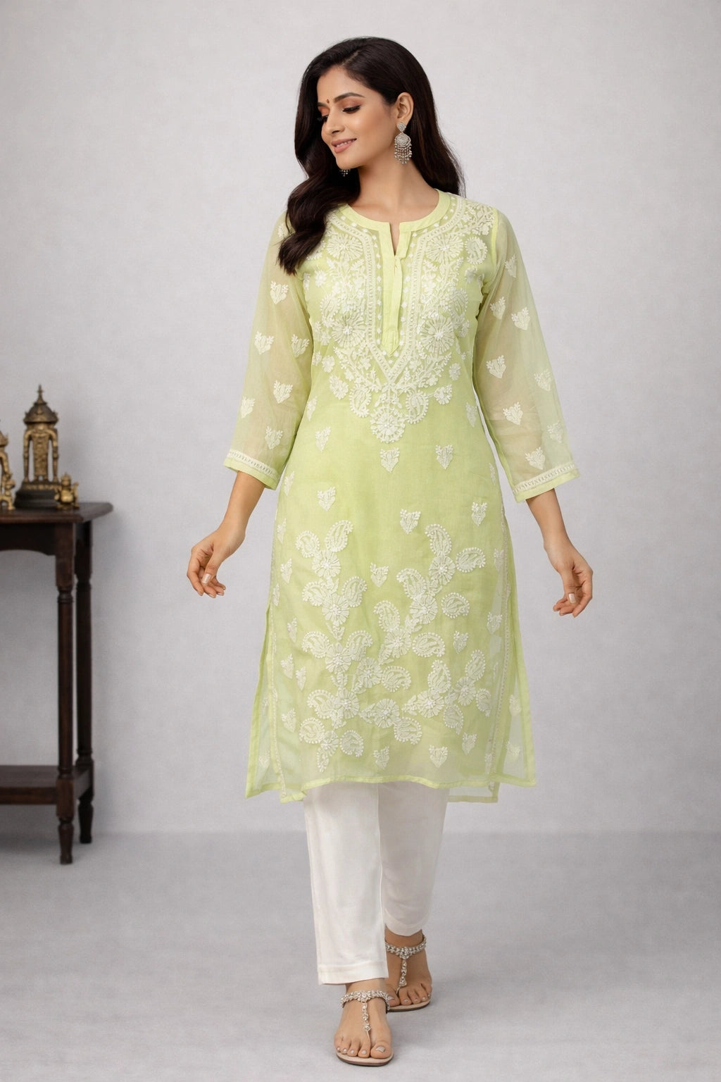 Woman wearing a light green embroidered kurta with white pants on a gray background