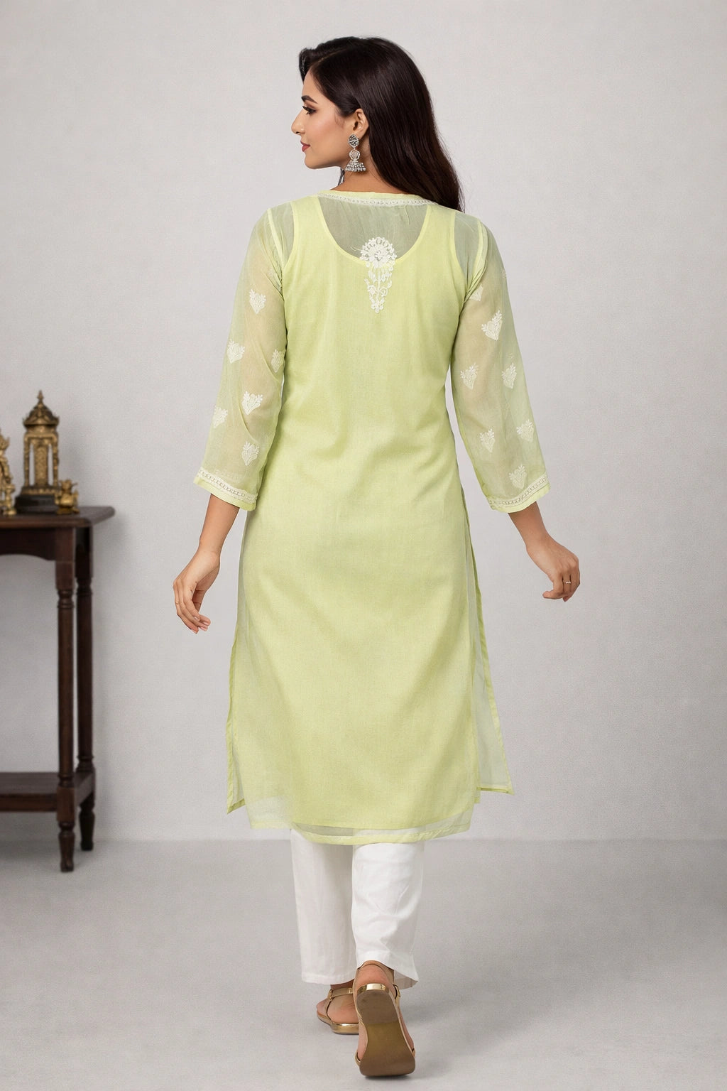 Woman wearing a light green kurta with white pants on a plain background