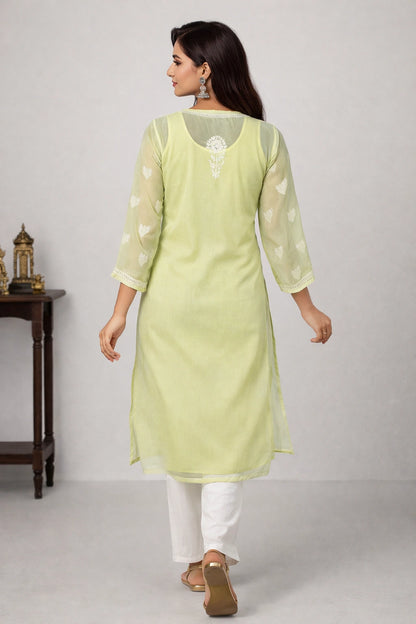 Woman wearing a light green kurta with white pants on a plain background