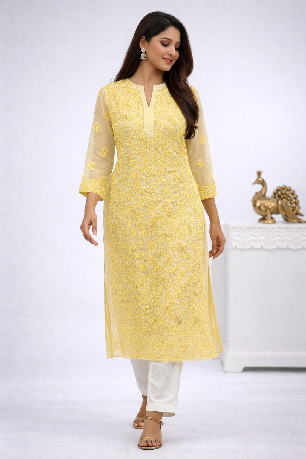 Woman wearing a yellow kurta with white pants on a white background