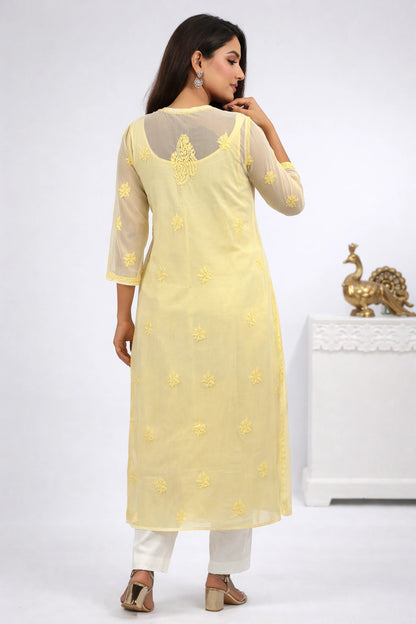 Woman wearing a yellow embroidered kurta with white pants on a white background
