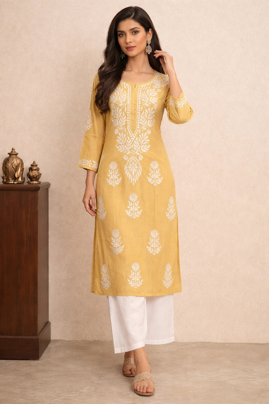 Woman wearing a yellow embroidered kurta with white pants against a beige background