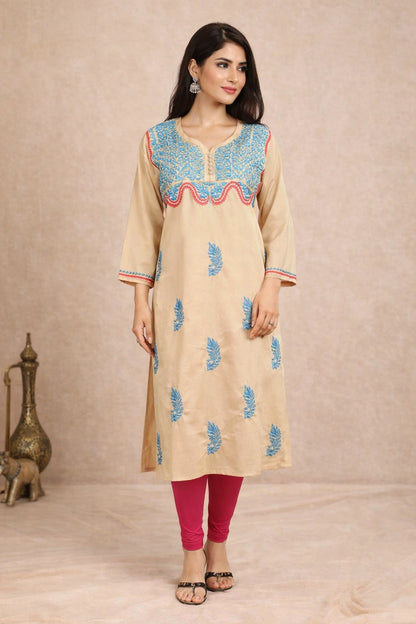 Woman wearing a beige kurta with blue embroidery against a beige background