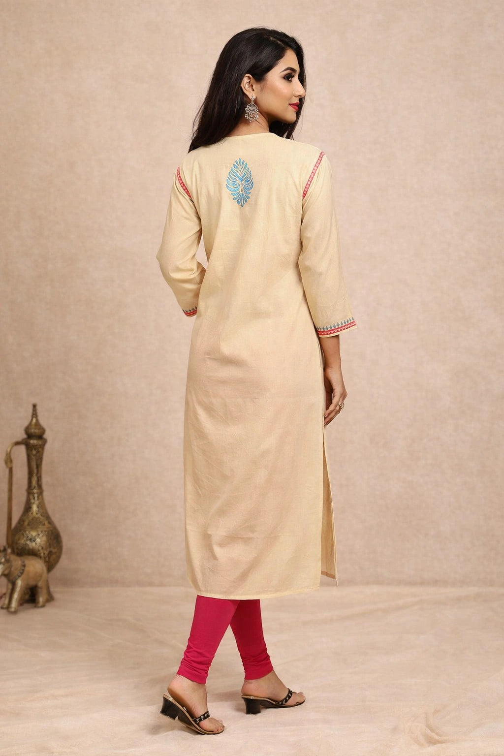 Woman wearing a beige kurta with pink leggings against a beige background