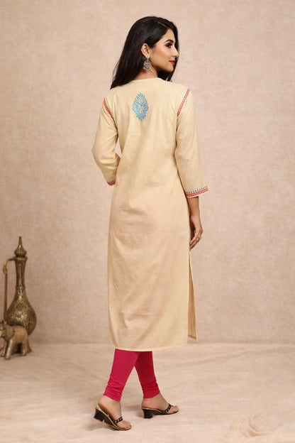 Woman wearing a beige kurta with pink leggings against a beige background
