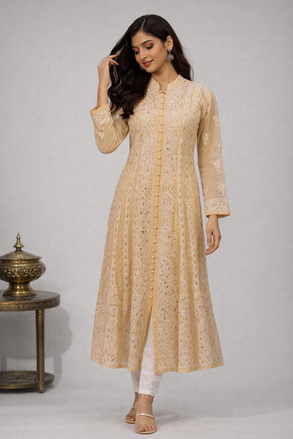Woman wearing a beige embroidered kurta with white pants against a gray background