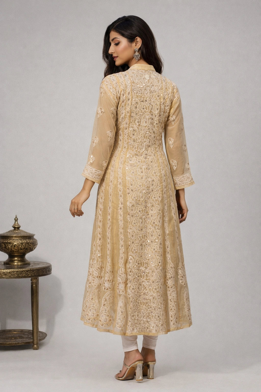 Woman wearing a beige embroidered kurta with white pants against a gray background