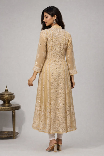 Woman wearing a beige embroidered kurta with white pants against a gray background