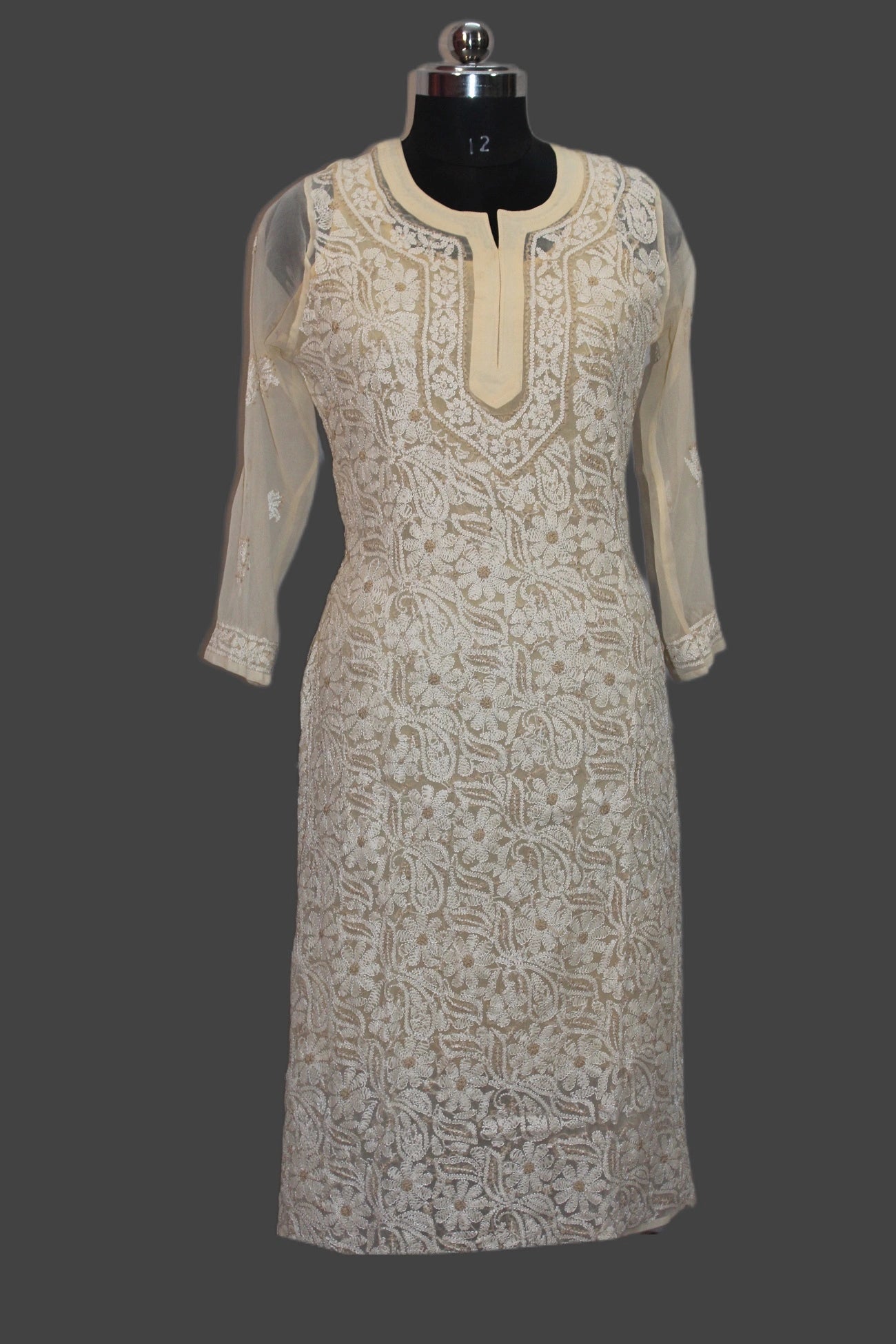 Beige embroidered dress on a mannequin against a gray background