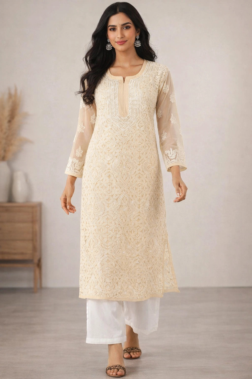 Woman wearing a beige embroidered kurta with white pants in a minimalistic setting.