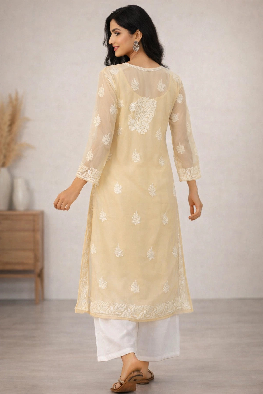 Woman wearing a beige embroidered kurta with white pants in a minimal indoor setting