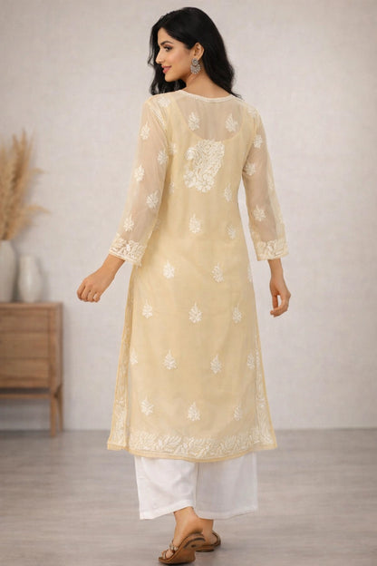 Woman wearing a beige embroidered kurta with white pants in a minimal indoor setting
