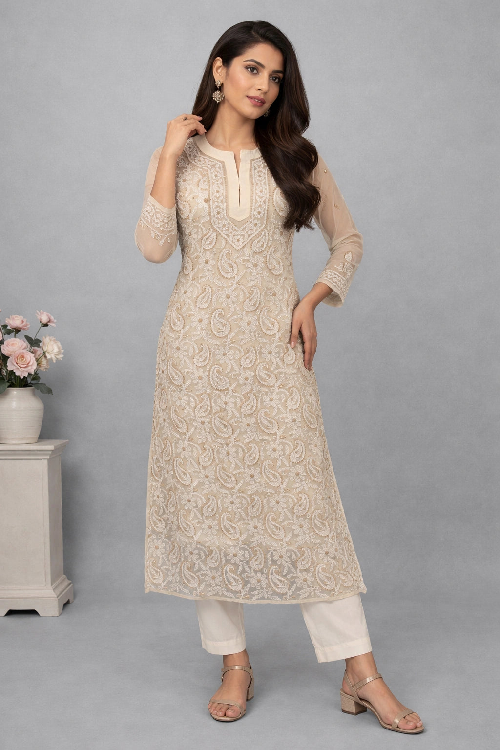 Woman wearing a beige embroidered kurta with white pants on a gray background