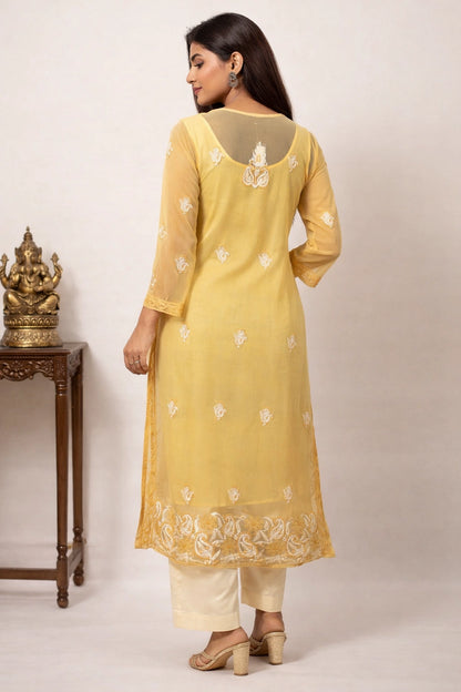 Woman wearing a yellow embroidered kurta with white pants against a neutral background
