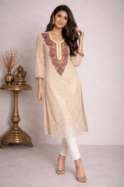 Woman wearing a beige embroidered kurta with white pants in a minimalistic setting.