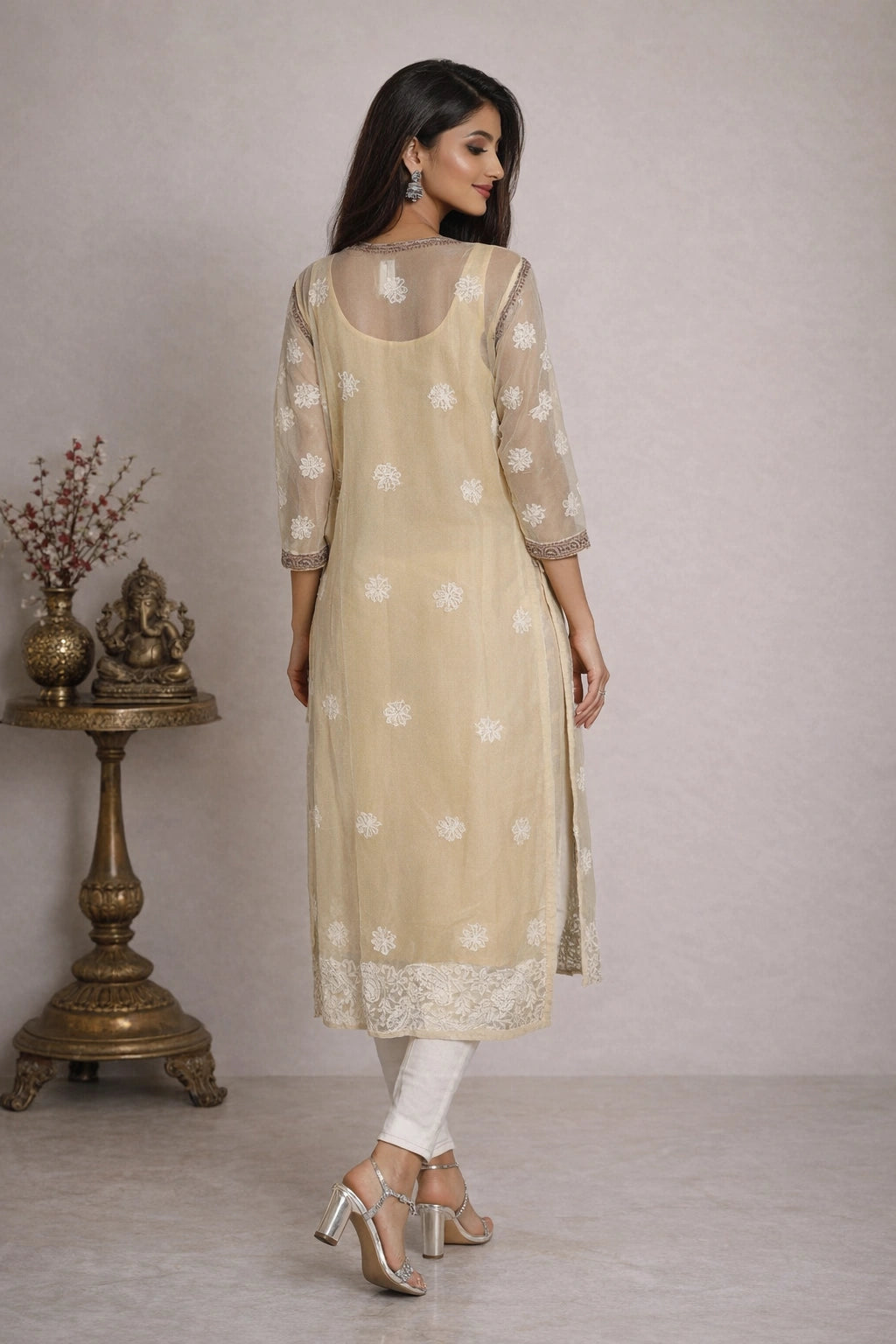 Woman wearing a beige kurta with white floral patterns in a minimalistic setting.