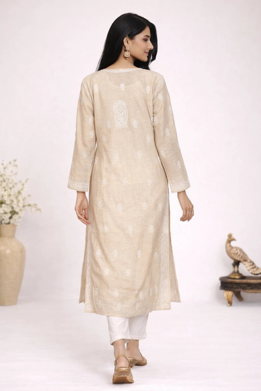 Woman wearing a lucknowi chikankari beige kurta with white pants on a white background