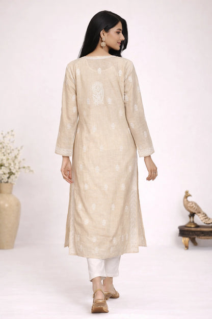 Woman wearing a lucknowi chikankari beige kurta with white pants on a white background