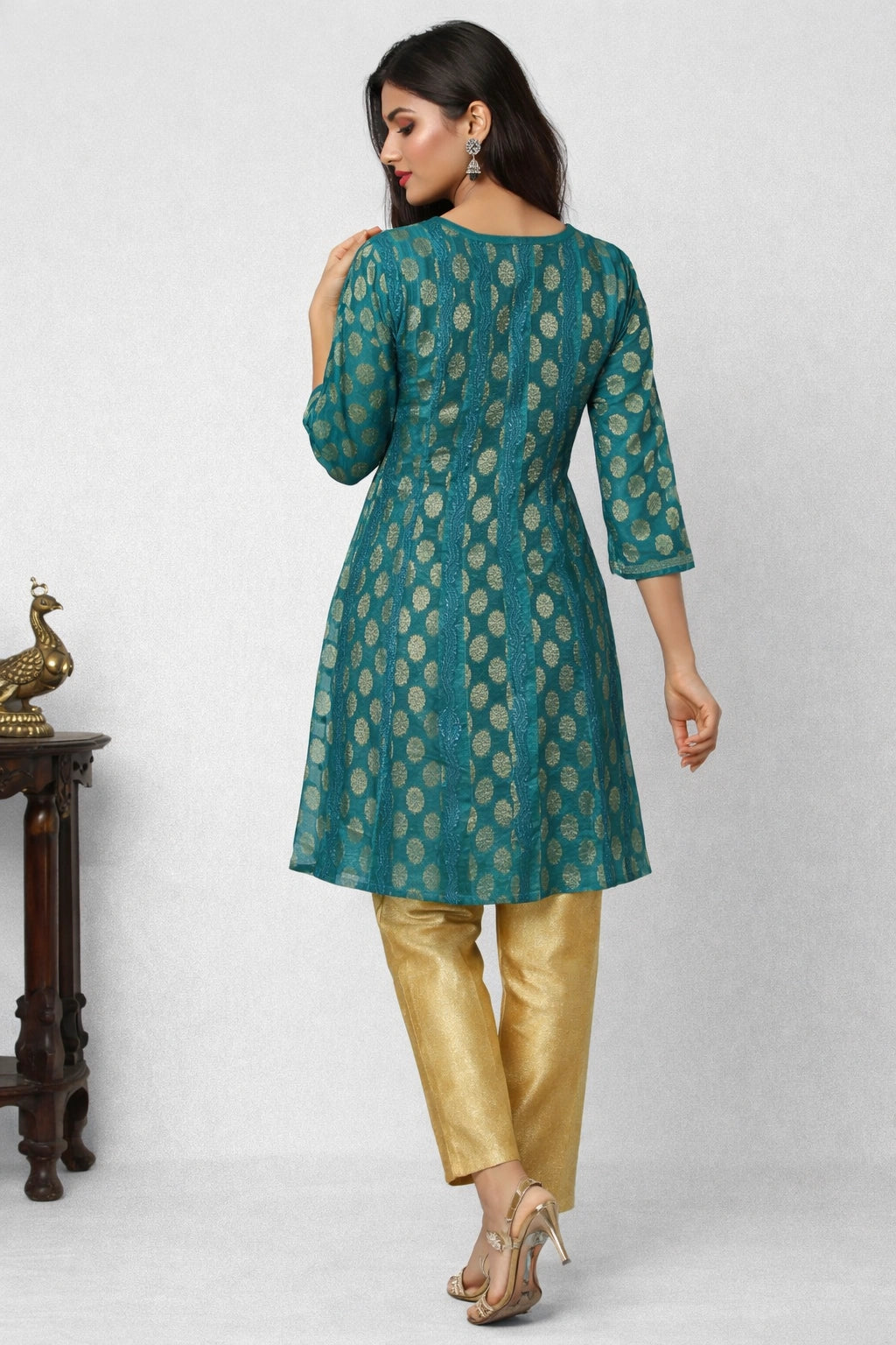 Woman wearing a green and gold traditional outfit with a white background