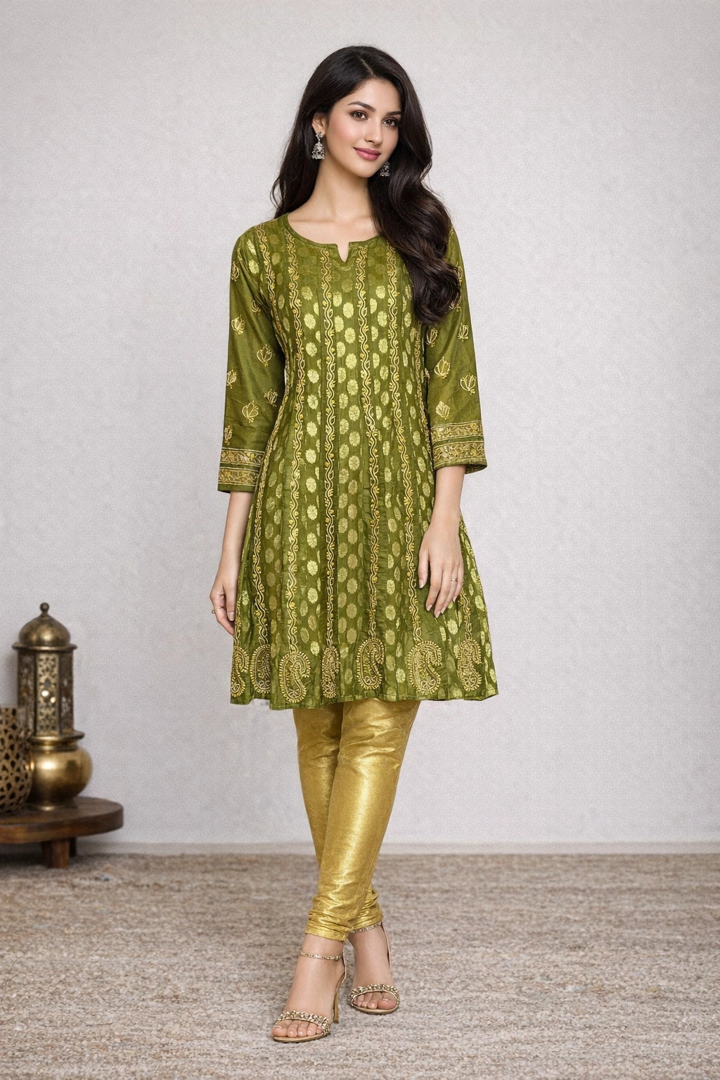 Woman wearing a green embroidered kurta with gold pants on a plain background
