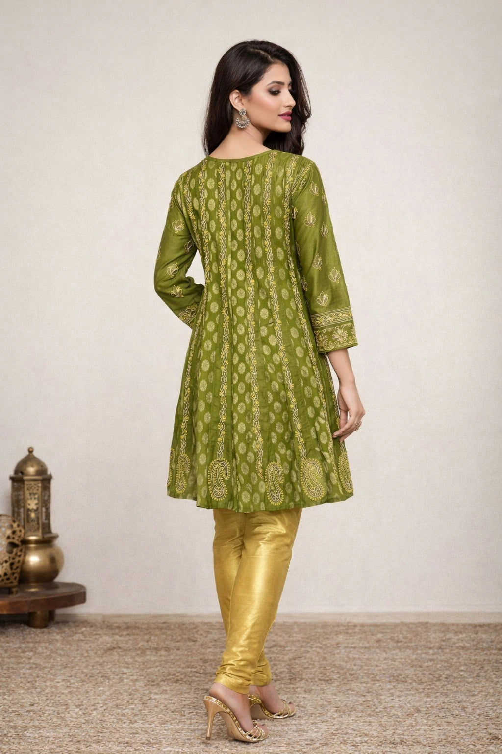 Woman wearing a green and gold traditional outfit with a plain background