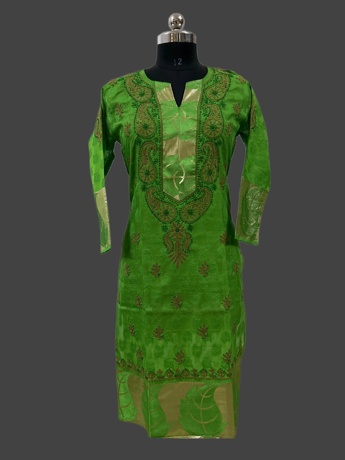 A bright green traditional long kurta with gold embroidery, displayed on a black mannequin against a dark gray background.