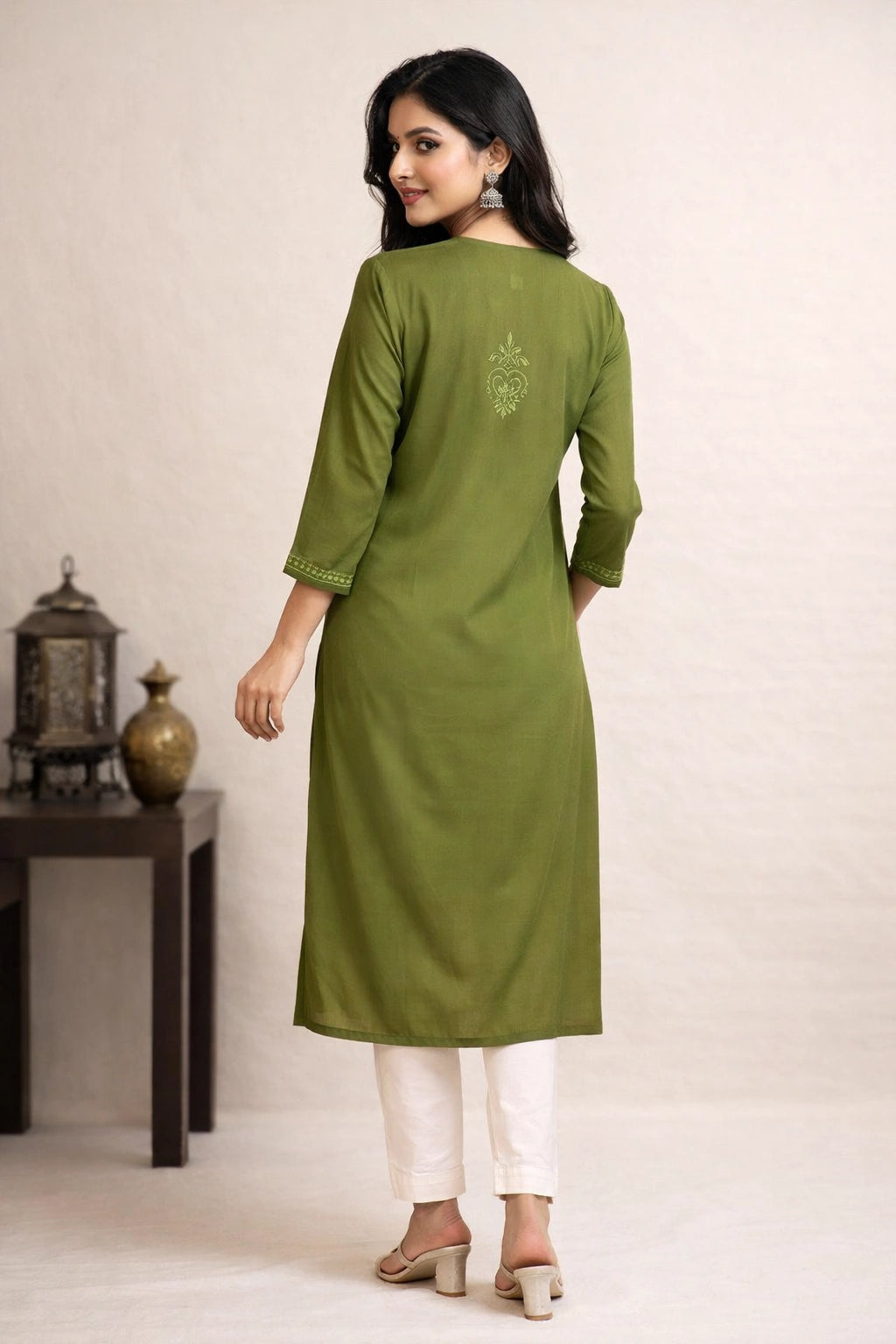 Woman wearing a green kurta with white pants on a beige background