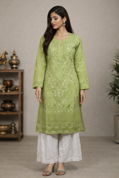 Woman wearing a green embroidered kurta with white pants in a neutral setting.