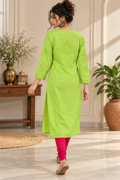 A woman wearing a bright lime green kurta with three-quarter sleeves and a subtle embroidered design on the back, paired with bright pink leggings, walking in a decorated indoor setting.