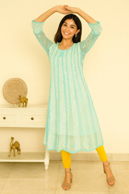Woman wearing a green embroidered kurta with white patterns on a beige background