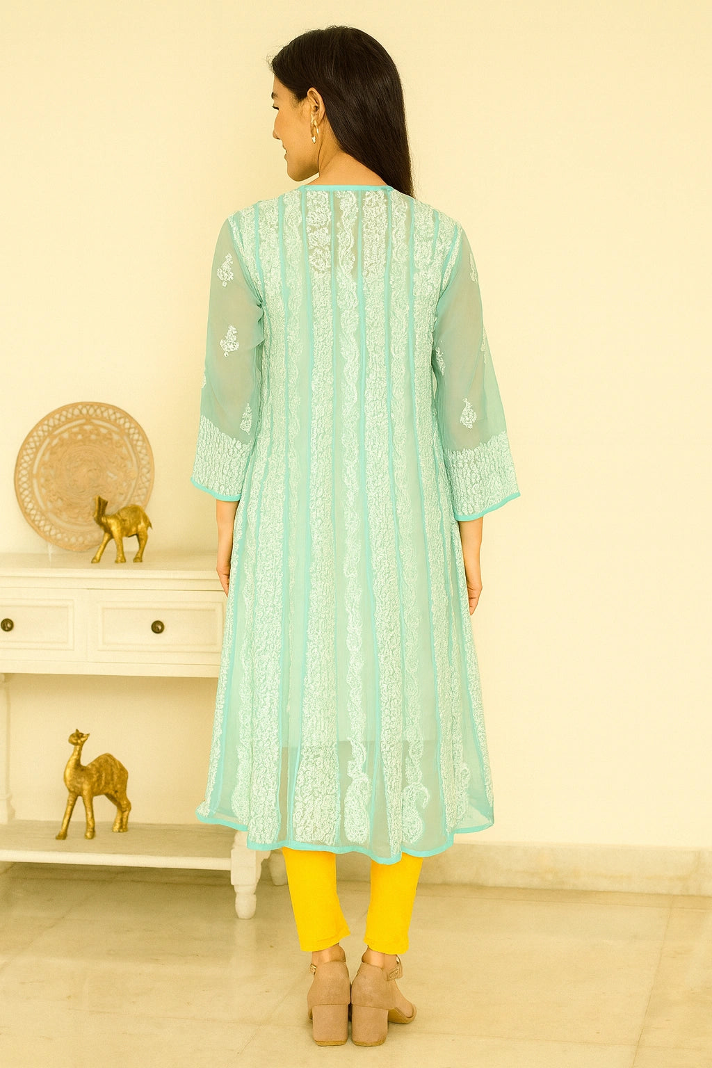 Woman wearing a green embroidered dress against a beige background