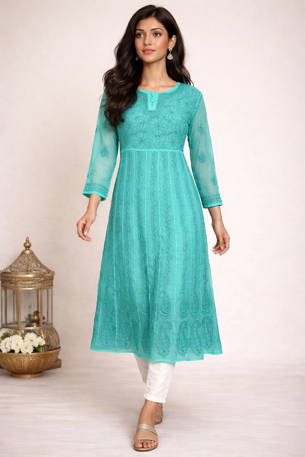 Woman wearing a lucknowi chikankari teal kurta with white pants on a light background