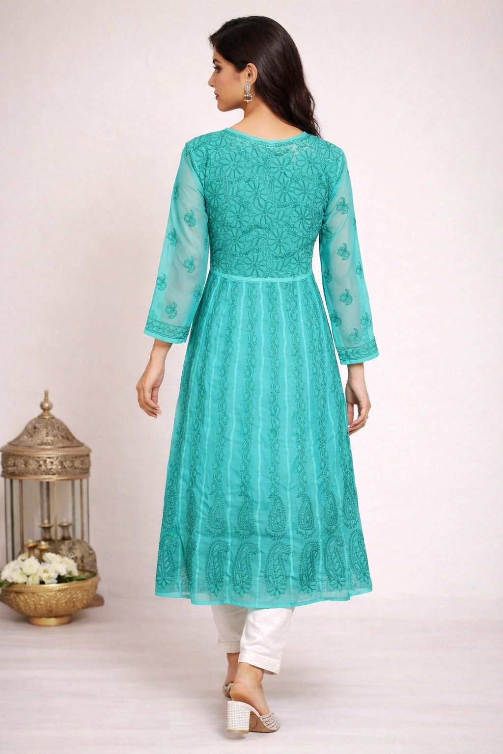 Woman wearing a teal embroidered kurta with white pants on a light background