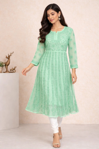 Woman wearing a light green embroidered kurta with white pants against a neutral background