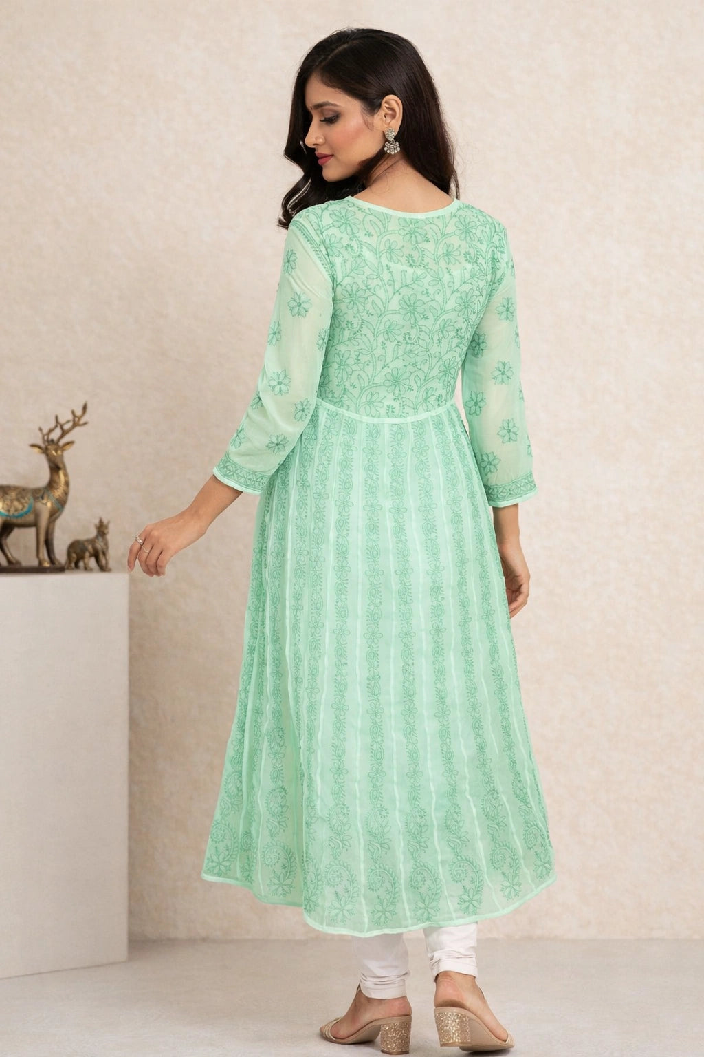 Woman wearing a light green embroidered kurta with white pants against a beige background