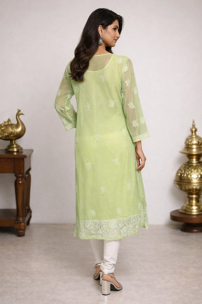 Woman wearing a light green kurta with white embroidery in a minimalistic setting.