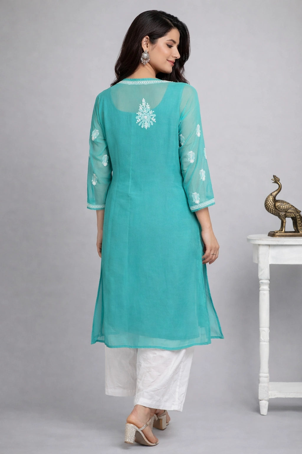 Woman wearing a chikankari teal kurta with white embroidery on a gray background