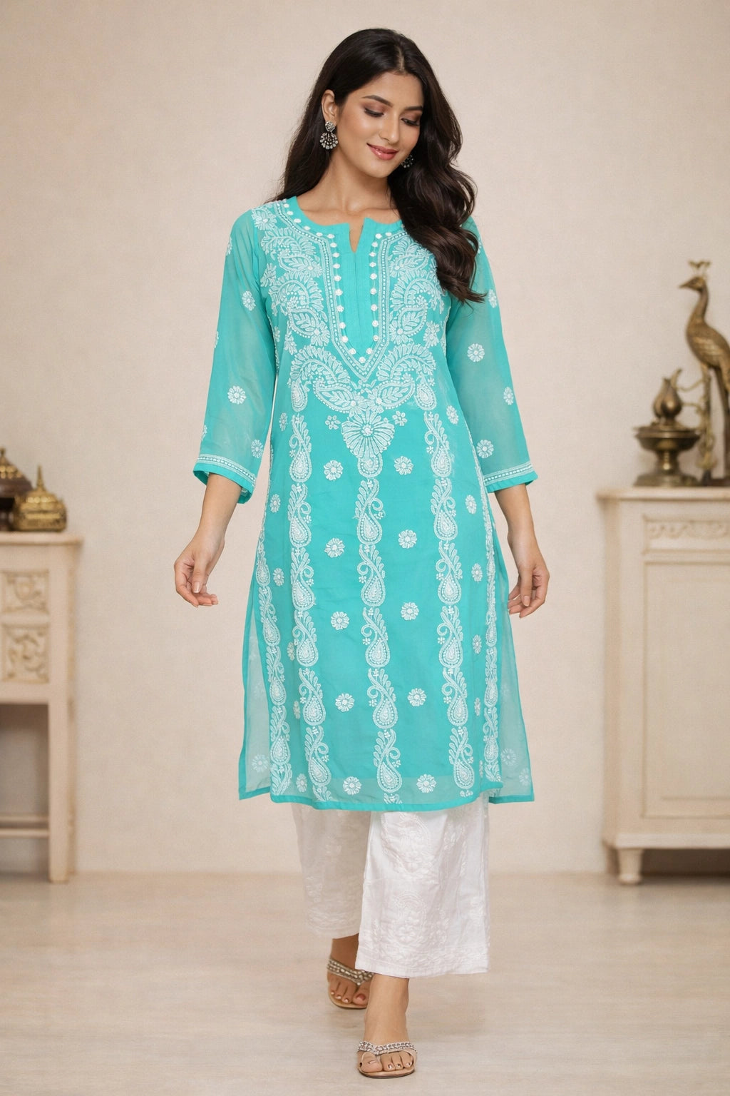 Woman wearing a turquoise embroidered kurta with white pants in an indoor setting.