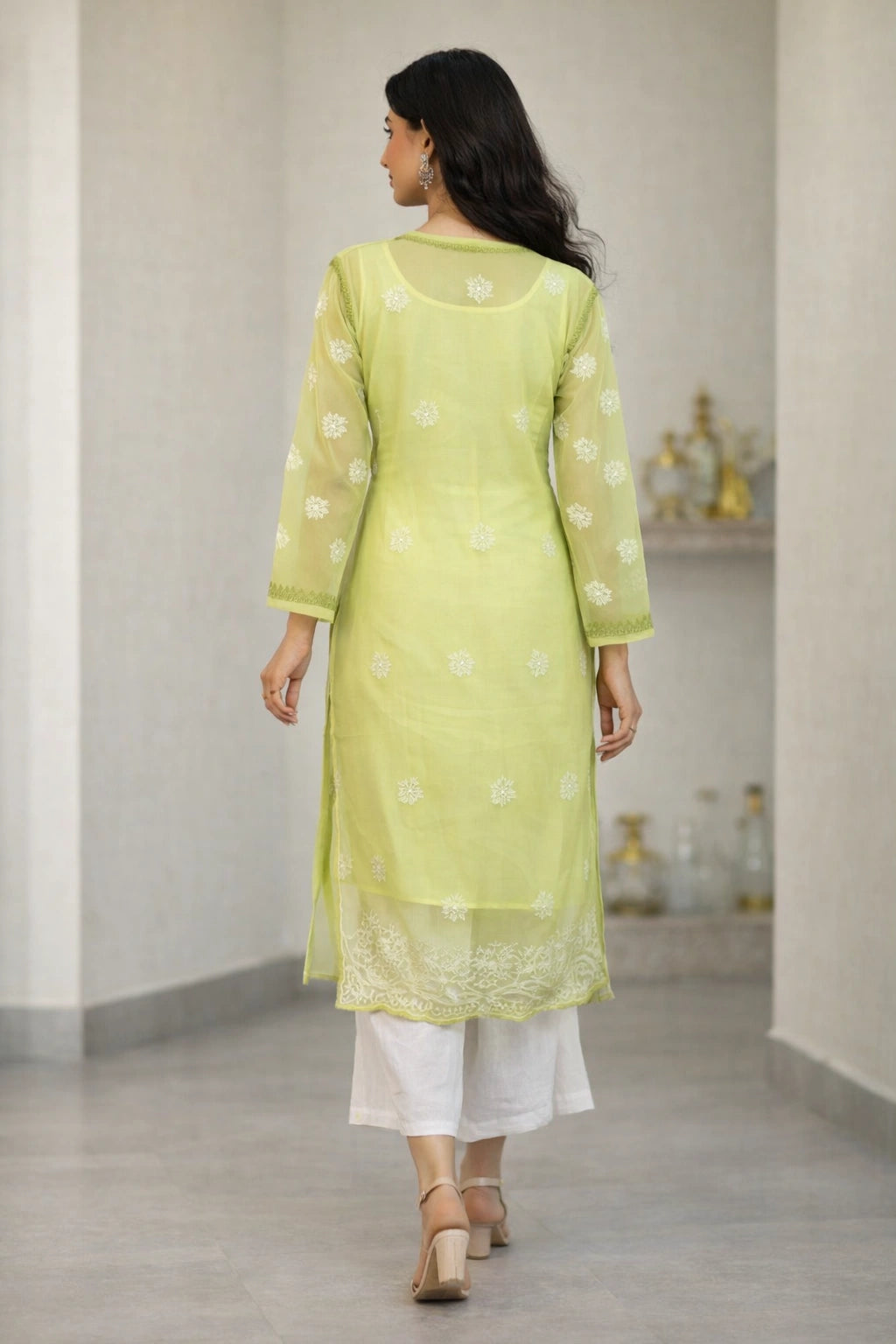 Woman wearing a light green kurta with white patterns in a minimal indoor setting.