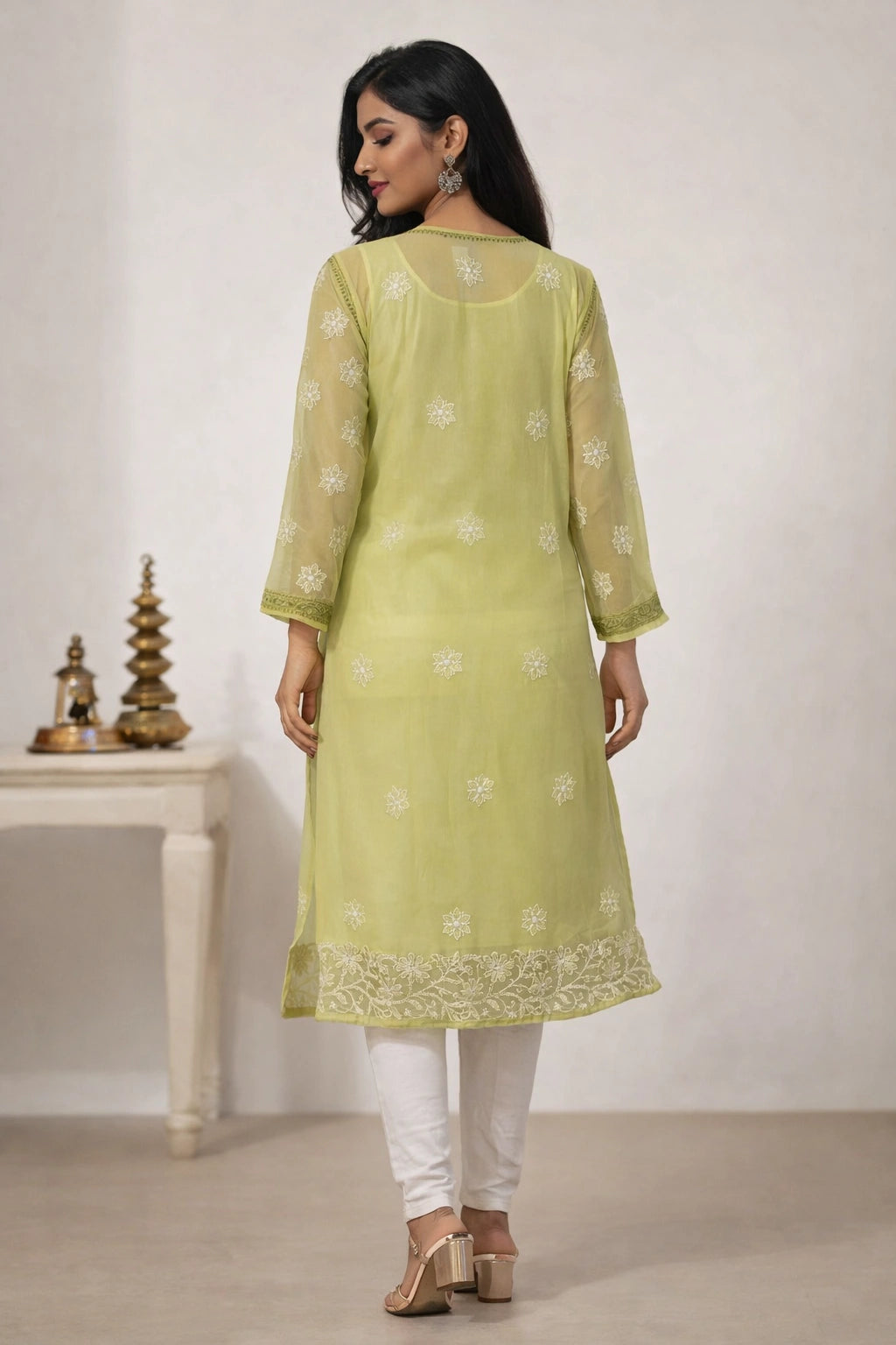 Woman wearing a light green kurta with white embroidery in a minimal setting.